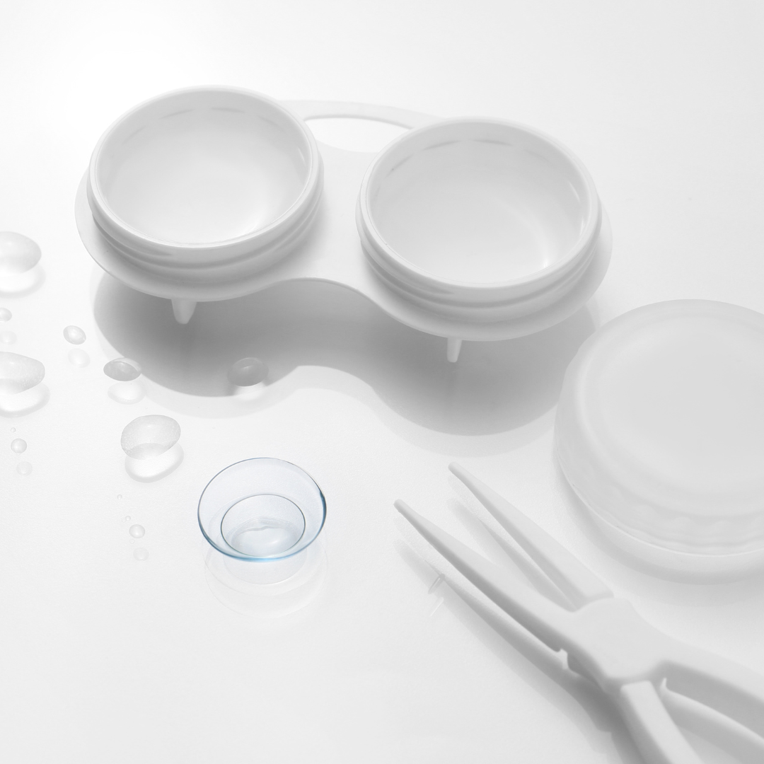 Contact lens case with the lid, tweezers and contact lens next to it