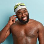 A candid shot of a cheerful man who has water in his ear after going swimming