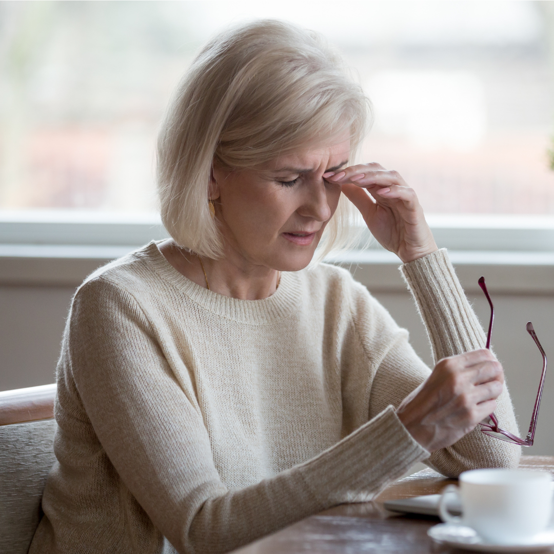Middle aged woman, sat at a table, removed glasses, rubbing eyes, dry eye, glaucoma