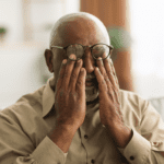 Man with glasses on forehead rubbing eyes, glaucoma. Alcohol and Eyesight. Diabetic Retinopathy. Diabetic Eye Disease