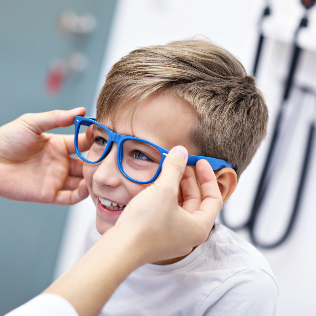 Boy in opticians having blue glasses fitted